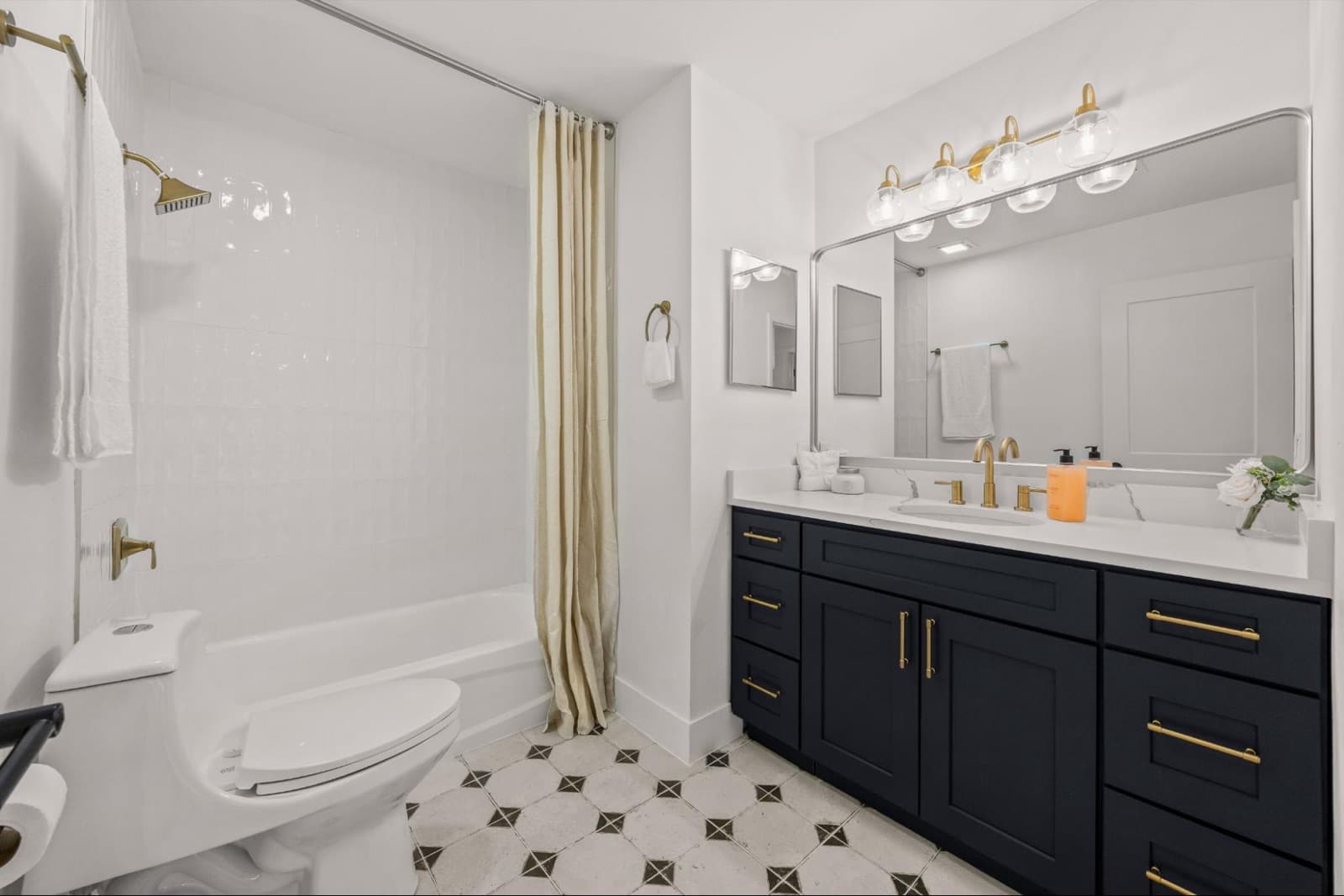 After: a fully remodeled bathroom with a navy vanity and gold fixtures